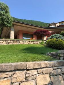 a house with a stone wall in front of a yard at VILLA COLLE in Ranzanico