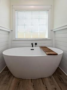 bañera blanca grande en el baño con ventana en The Waverly 100 Inn at Old Beach en Virginia Beach
