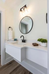 uma casa de banho branca com um lavatório e um espelho em The Waverly 100 Inn at Old Beach em Virginia Beach