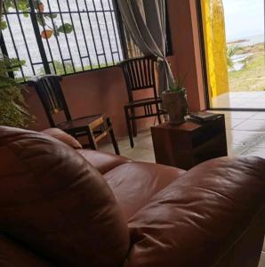 a brown leather couch in a living room with a window at Hostal Apartamento con salida al mar in Puerto Limón