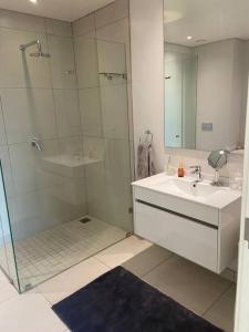a bathroom with a shower and a sink and a mirror at Load-Shedding Free Trendy 2-bed 2-bath Apartment in Johannesburg