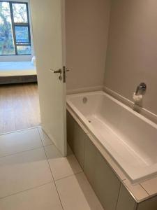 a white bathroom with a tub and a window at Load-Shedding Free Trendy 2-bed 2-bath Apartment in Johannesburg