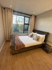 a large bed in a room with a window at Load-Shedding Free Trendy 2-bed 2-bath Apartment in Johannesburg