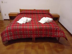 Una cama roja con dos almohadas blancas. en Casa vacanze Monica, en Campodenno