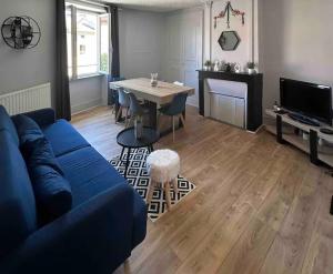 a living room with a blue couch and a table at Gîte Cosy - 72m2 - Hyper Centre - Tout équipé in Langeac