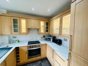 una cocina con armarios de madera y encimeras blancas en Stylish Two Bedroom Flat Colindale, NW9 close to station, en Colindale
