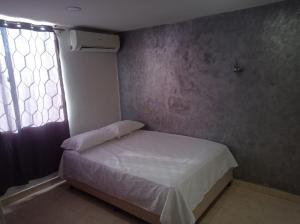 een kleine slaapkamer met een bed en een raam bij Casa Blanca Ciudad Jardín in Barranquilla