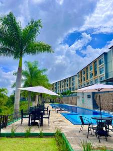 バナネイラスにあるLindo Apartamento no Condomínio Alto da Serra Villas de Bananeirasのプールの横にテーブルとパラソルがあるホテル +24枚の写真