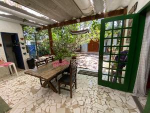 a patio with a wooden table and a green door at Casa à beira do rio Jaguareguava na Mata Atlântica em Bertioga SP in Bertioga
