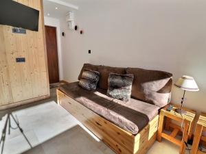 ein Wohnzimmer mit einem braunen Sofa und einem TV in der Unterkunft Studio Méribel, 1 pièce, 2 personnes - FR-1-182-167 in Méribel