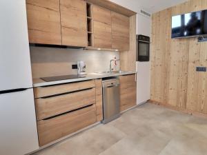 eine Küche mit Holzschränken und Küchengeräten aus Edelstahl in der Unterkunft Studio Méribel, 1 pièce, 2 personnes - FR-1-182-167 in Méribel