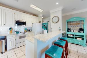 una cocina con armarios blancos y una isla azul con taburetes en Smiles in Isla Del Sol en Galveston