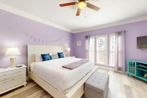 1 dormitorio con paredes moradas y 1 cama con ventilador de techo en Smiles in Isla Del Sol en Galveston