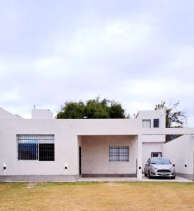 samochód zaparkowany przed białym domem w obiekcie Casa Valle Viejo w mieście San Fernando del Valle de Catamarca