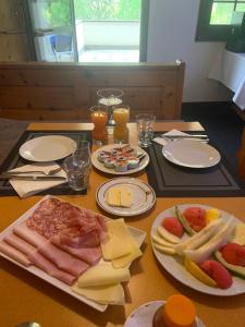 una mesa con platos de carne, queso y bebidas en Bed and Breakfast Darlux, en Bergün