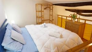 um quarto com uma grande cama branca e uma cómoda em madeira em Saint Mary House em Alghero