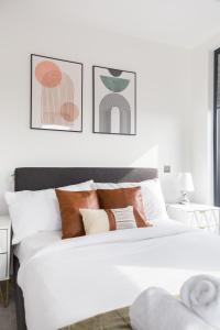 a bedroom with a white bed with three pictures on the wall at The Vale - Luxury Apartments in London