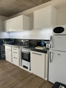 una cocina con electrodomésticos blancos y armarios blancos en Pension Irivai appartement PUATOU 1 chambre bord de mer, en Uturoa