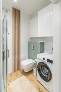 a bathroom with a washing machine and a toilet at Kraków Business Suite - City View with Balcony & Parking by Rentujemy in Krakow