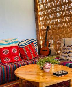 ein Wohnzimmer mit einem Sofa und einem Tisch mit einer Gitarre in der Unterkunft kosasurfmorocco in Aourir