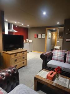 ein Wohnzimmer mit einem Flachbild-TV und Ledermöbeln in der Unterkunft THE MOORINGS in Broadford