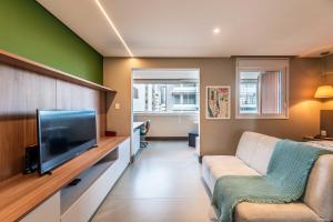 ein Wohnzimmer mit einem Sofa und einem Flachbild-TV in der Unterkunft Pinheiros Faria Lima, Novo, 38M2, WIFI700MB - Traveller Awards 2024 in São Paulo