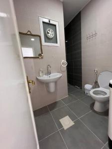 bagno con lavandino, servizi igienici e specchio di The guset house a Kerak
