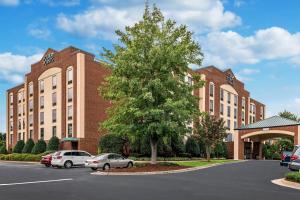 a large brick building with cars parked in a parking lot at Four Points by Sheraton Greensboro Airport in Greensboro