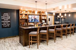 a bar in a restaurant with wooden stools at Four Points by Sheraton Greensboro Airport in Greensboro