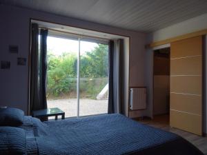 een slaapkamer met een bed en een groot raam bij Datcha Bourguignonne, Chambres & Gîte in Maconge