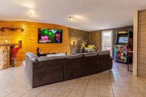 sala de estar con sofá grande y TV de pantalla plana en Le Garage, en Lorp Sentaraille