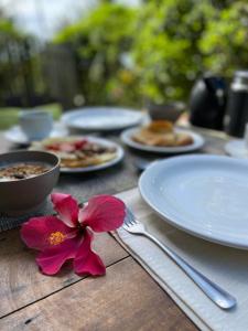 een tafel met borden en een bloem erop bij Casa Hibiscus in Ilha de Boipeba