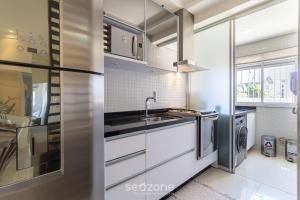 una cucina bianca con lavandino e piano cottura di Lindo apto confortável e bem localizado MOS104 a Florianópolis
