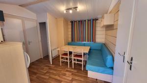 Habitación pequeña con mesa y sofá azul en Anne Marie Touzani, en Boofzheim
