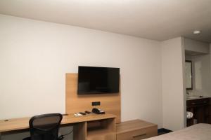 a room with a desk and a television on a wall at Quality Inn Portland Airport PDX in Portland