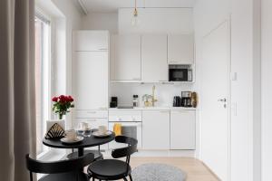 uma cozinha branca com uma mesa preta e cadeiras em Great location, quiet and new with balcony&cafe em Tampere