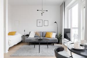 a white living room with a couch and a table at Great location, quiet and new with balcony&cafe in Tampere