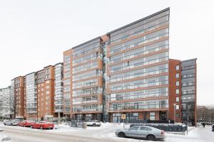 a large building with cars parked in a parking lot at Great location, quiet and new with balcony&cafe in Tampere