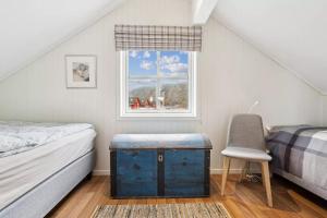 een slaapkamer met een bed, een raam en een stoel bij Waterfront cabin in the middle of Lofoten in Ballstad