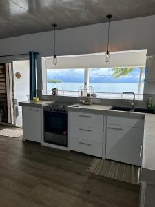 a kitchen with a sink and a stove top oven at Pension Irivai, appartement UO UO 3 chambres vue mer in Uturoa