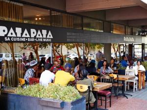 a group of people sitting at tables outside a restaurant at Sun's spacious apartment in Johannesburg