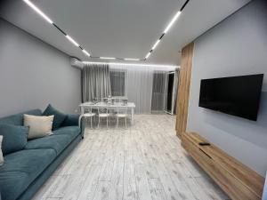 sala de estar con sofá azul y TV en Квартира - студия 72 кв.м, en Uralsk