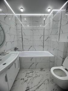 baño blanco con bañera y aseo en Квартира - студия 72 кв.м, en Uralsk