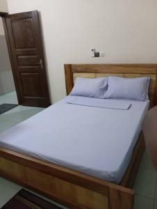 1 cama con marco de madera y colchón blanco en Superbe Appartement COTONOU Place de L'étoile rouge, en Cotonou