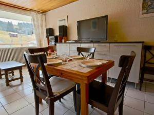 uma sala de jantar com uma mesa com cadeiras e uma televisão em Appartement Chamrousse, 2 pièces, 4 personnes - FR-1-549-69 em Chamrousse