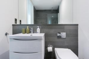 a white bathroom with a sink and a toilet at The Vale - Luxury Apartments in London