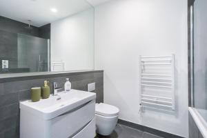 a bathroom with a white sink and a toilet at The Vale - Luxury Apartments in London