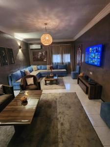 a living room with a blue couch and a tv at Aprt 4 Family in Marrakech