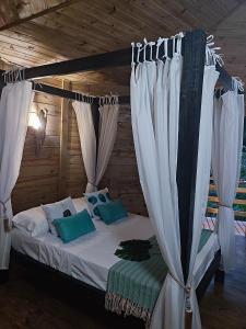 un letto con tende bianche in una stanza di Casa na Árvore - Chalé Quemeninho a Apiaí
