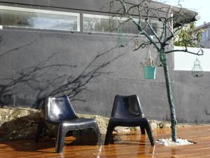 two black chairs sitting next to a tree at Guerras House in Porto